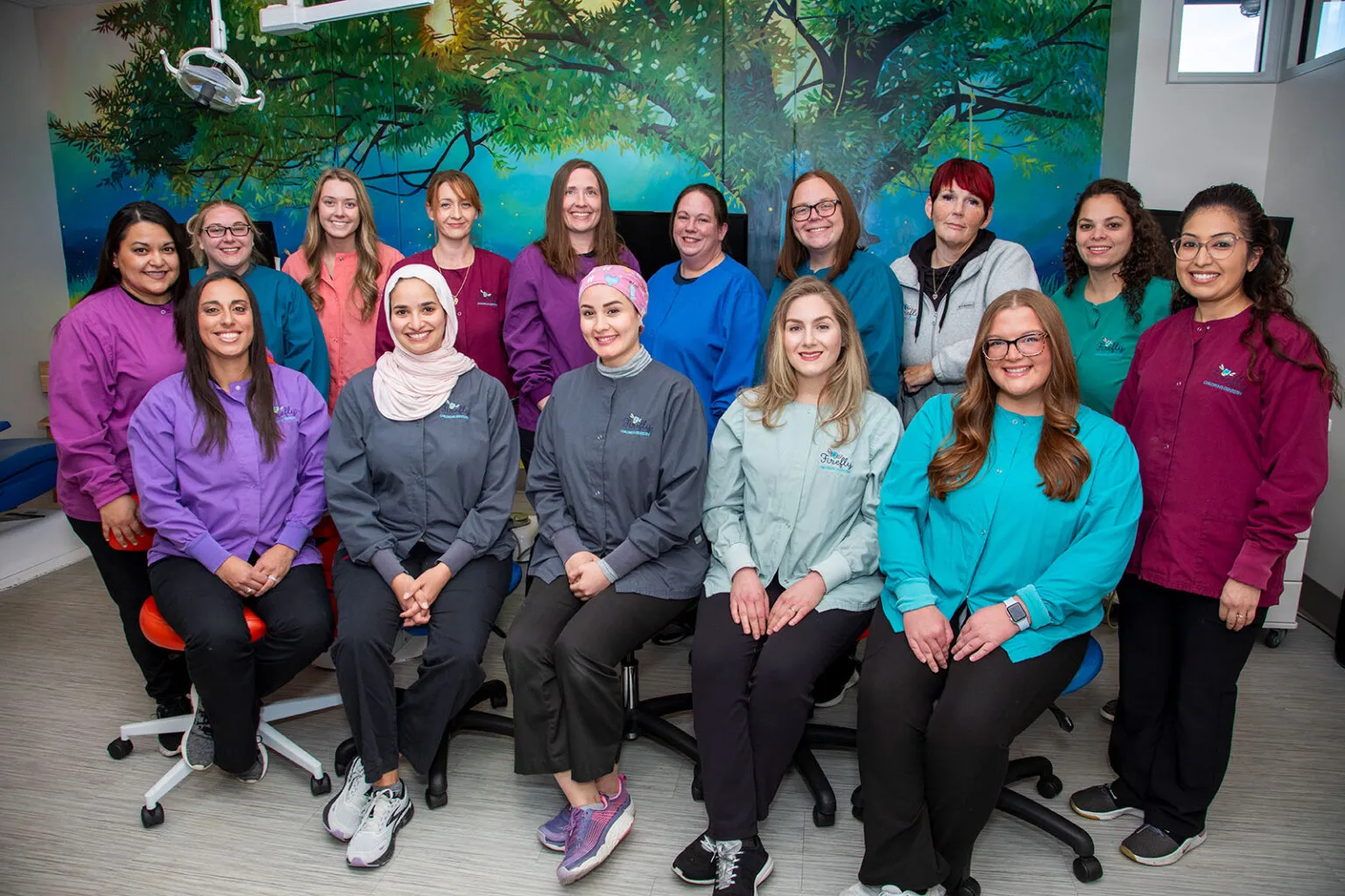 The Firefly Children's Dentistry team in front of the office's enchanted-forest mural